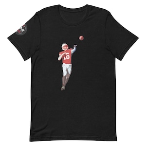 May include: Black t-shirt with a graphic of a football player in a red jersey throwing a football.