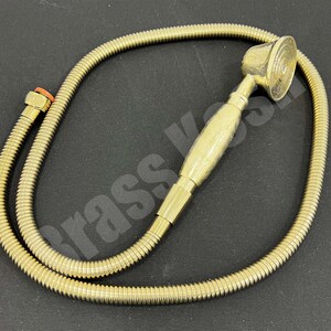 Pu&ograve; includere: Un soffione doccia e un tubo flessibile in ottone. Il soffione ha un design circolare con un manico strutturato. Il tubo &egrave; di design flessibile e ondulato. I raccordi sono color ottone.