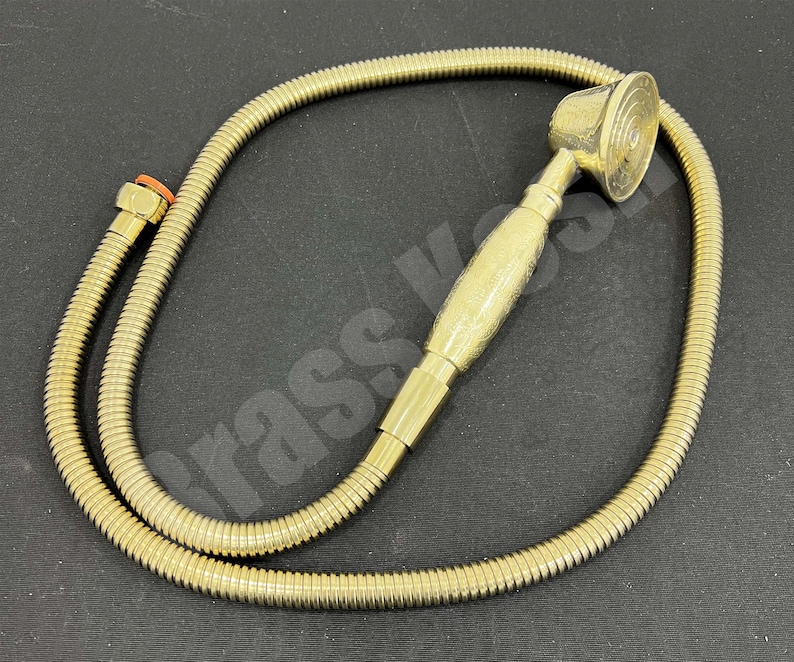 Pu&ograve; includere: Un soffione doccia e un tubo flessibile in ottone. Il soffione ha un design circolare con un manico strutturato. Il tubo &egrave; di design flessibile e ondulato. I raccordi sono color ottone.