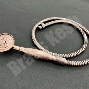 Pu&ograve; includere: Soffione doccia color rame con flessibile abbinato. Il soffione ha una piastra di spruzzo circolare con pi&ugrave; fori. L'impugnatura presenta un design ornato e inciso. Il tubo &egrave; in stile metallico ondulato.