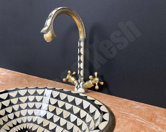 May include: A black and white patterned sink with a gold and black faucet. The sink is made of a mosaic of small, geometric shapes.