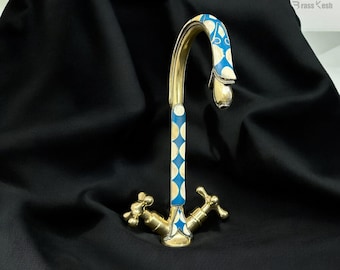 May include: A gold faucet with a blue and white patterned design. The faucet has two handles and a high spout.