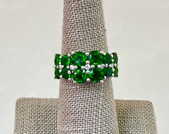 May include: A silver ring with a band of green gemstones and small white diamonds.