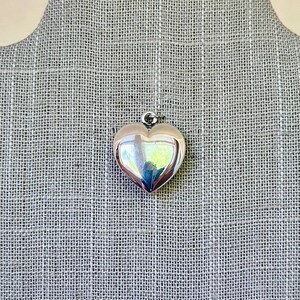 May include: A silver heart-shaped pendant charm. The charm is smooth and shiny.