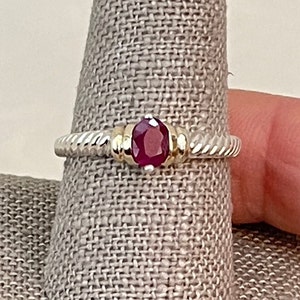 Puede incluir: Un anillo de plata con una banda trenzada y una piedra preciosa roja engastada en un engaste de oro.