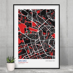May include: A black and white map of San Siro, a neighborhood in Milan, Italy. The map is printed on white paper and framed in a black frame. The map shows the streets and buildings of the neighborhood. The text "San Siro Established 1926 45.48° N 9.12° E" is printed in blue at the bottom of the map. The text "20151 Milan, Italy" is printed in red at the bottom of the map.