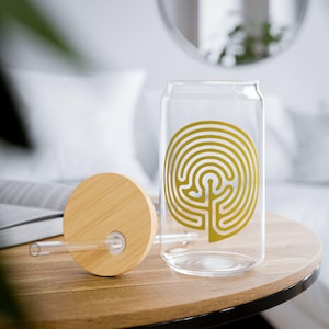 May include: A glass reusable water bottle with a bamboo lid and straw. The bottle features a gold labyrinth design on the side.