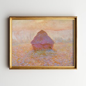May include: A framed painting of a haystack in a field, rendered in a soft, impressionistic style. The artwork features a golden frame and a color palette of pinks, oranges, and blues, evoking a serene landscape scene.