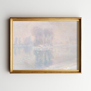 May include: A framed landscape painting with a gold-colored frame. The artwork depicts a misty river scene with trees and their reflections in the water. The color palette is soft, with muted blues, whites, and hints of pink.