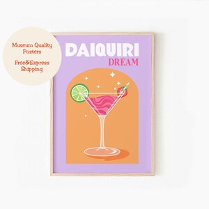 May include: A retro-style poster with a purple background and a peach-colored arch. The arch features a martini glass filled with a pink drink, a lime wedge, a strawberry, and a straw. The text "DAIQUIRI DREAM" is in white letters at the top of the poster.