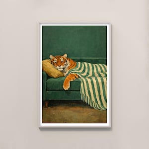 May include: A framed print of a tiger resting on a green sofa with a yellow pillow and a striped blanket. The tiger has orange and black stripes and is lying down, appearing relaxed. The artwork has a vintage aesthetic.