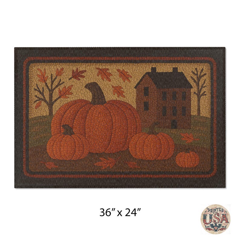 May include: Rectangular doormat featuring a fall harvest scene. The design includes three orange pumpkins, a brown house, and falling leaves. The mat measures 36 inches by 24 inches.