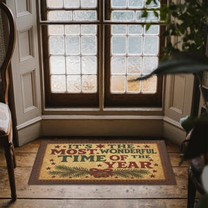 May include: A rectangular doormat with the text "IT'S THE MOST WONDERFUL TIME OF THE YEAR" in red, green, and yellow. The mat features a brown border and festive holiday imagery, including stars, pine branches, and a bow.
