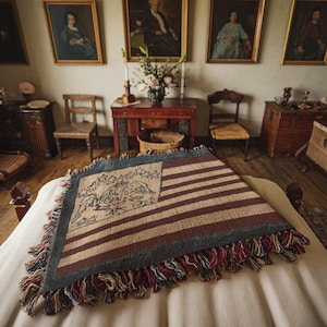 Pode incluir: Uma manta de estilo vintage com a bandeira americana com um design de águia tecido no centro. A manta é feita de um tecido macio e texturizado e tem uma borda com franjas.