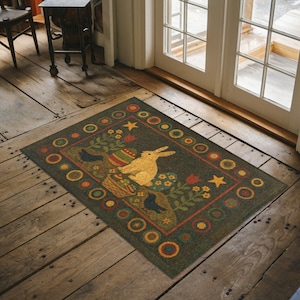 May include: A rectangular Easter-themed doormat with a dark green background. The mat features a yellow rabbit, decorated eggs, flowers, and birds. The border has a repeating pattern of circles and stars. The mat is placed on a wooden floor.