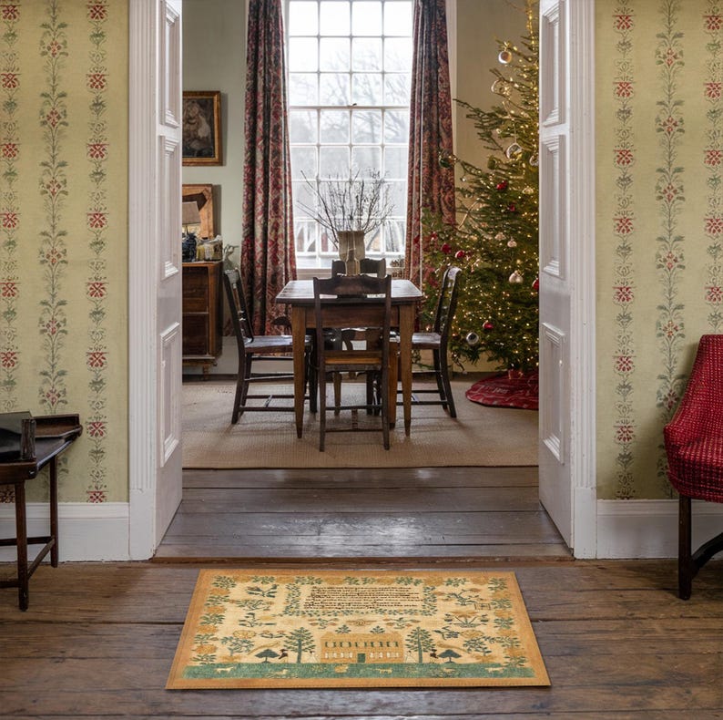 May include: A brown and beige patterned doormat with a Christmas tree design and the text "O Come, O Come Emmanuel" in a green font. The doormat is placed in front of a doorway with a wooden floor and a Christmas tree in the background.