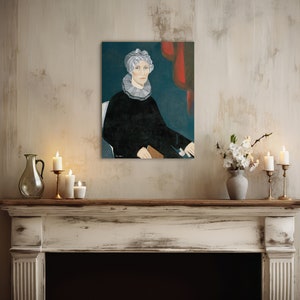 Op de afbeelding: Een schilderij van een vrouw met een witte muts en een zwarte jurk, zittend op een stoel met een rood gordijn op de achtergrond. Het schilderij hangt aan de muur boven een witte schouw met kaarsen en een vaas met witte bloemen.