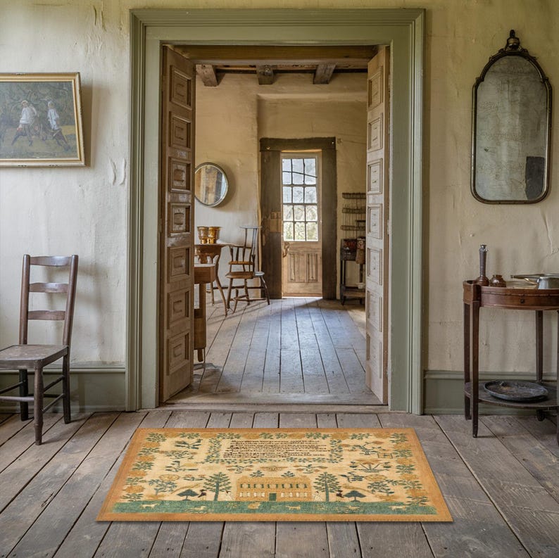 May include: A vintage-style rug with a beige background and green and brown accents. The rug features a house with a tree and flowers, and the text "Good Morning" is printed on the rug.