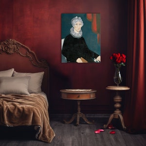 Op de afbeelding: Een bed in vintage stijl met een bruin hoofdeinde en een bruin deken. Een schilderij van een vrouw met een witte kraag en een rode achtergrond hangt aan de muur achter het bed. Een kleine houten tafel met een lade staat naast het bed, en een vaas met rode rozen staat op een houten tafel naast een rood gordijn.