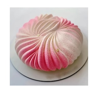 May include: A pink and white ombre cake with a swirl design and gold leaf accents. The cake is on a white cake board.