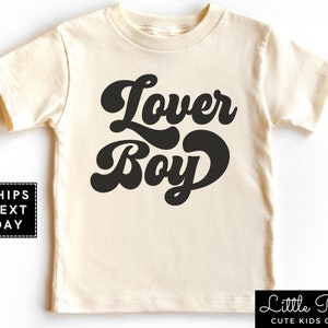 May include: A cream colored short-sleeved t-shirt with the text "Lower Boy" in black retro-style lettering.