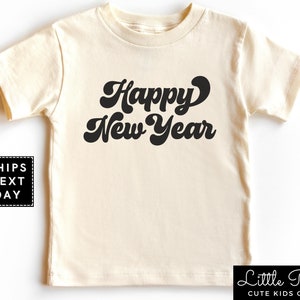 May include: A cream colored short-sleeved t-shirt with the text "Happy New Year" in a retro black font.