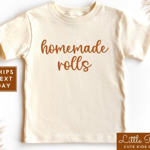 May include: A cream colored short-sleeved t-shirt with the text "homemade rolls" in brown lettering.