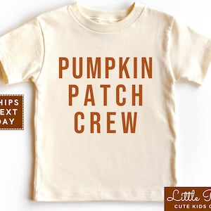May include: A cream colored short-sleeved t-shirt with the text "Pumpkin Patch Crew" in orange.