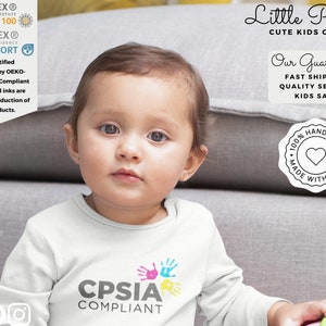 May include: A white long-sleeve shirt with a colorful handprint design and the text "CPSIA COMPLIANT". The shirt is made with 100% certified OEKO-TEX Standard 100 and CPSIA compliant materials. The image also includes a stamp that says "100% HANDMADE MADE WITH LOVE".