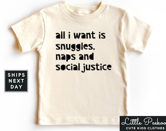 May include: A white toddler t-shirt with black text that reads "all i want is snuggles, naps and social justice".