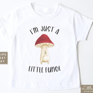 May include: White t-shirt with a cartoon mushroom graphic and the text "I'm just a little fungi".
