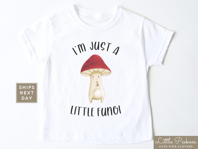 May include: White t-shirt with a cartoon mushroom graphic and the text "I'm just a little fungi".