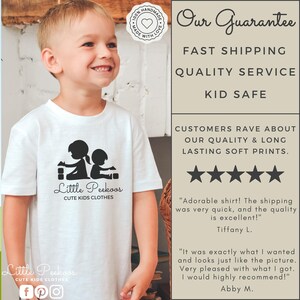 May include: A white t-shirt with a black graphic of two children playing with blocks. The text "Little Peekoos" and "Cute Kids Clothes" is printed below the graphic. The t-shirt is being worn by a young boy. The image also includes a text box with the words "Our Guarantee", "Fast Shipping", "Quality Service", "Kid Safe", and customer reviews.
