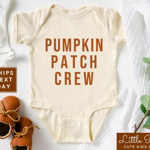 May include: A cream-colored baby onesie with the text "Pumpkin Patch Crew" in orange lettering.