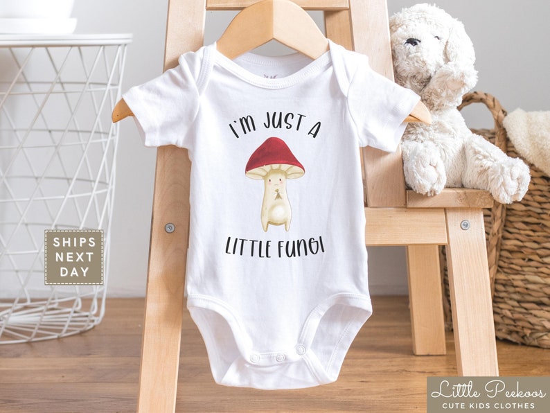 May include: White baby bodysuit with a red mushroom graphic and the text "I'm just a little fungi".