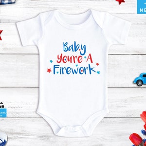 May include: White baby onesie with red, white, and blue stars and the text "Baby You're A Firework".