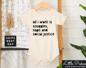 May include: A white baby onesie with black text that reads "all i want is snuggles, naps and social justice".