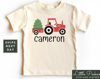 May include: A red toy tractor with a Christmas tree in the back. The tractor has black wheels and a yellow star on the tree. The text "cameron" is written below the tractor.