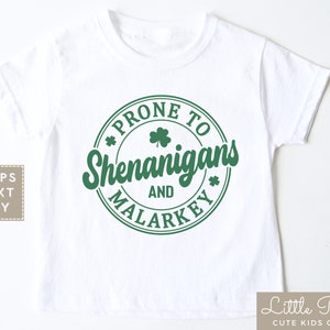 May include: White t-shirt with a green circle graphic that says "Prone to Shenanigans and Malarkey" with a shamrock design.