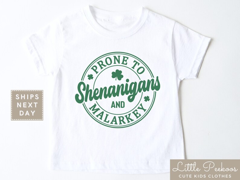 May include: White t-shirt with a green circle graphic that says "Prone to Shenanigans and Malarkey" with a shamrock design.