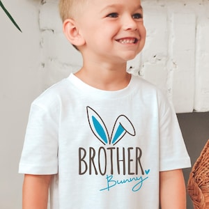 May include: A white t-shirt with a blue bunny ear graphic and the text "Brother Bunny" in black.