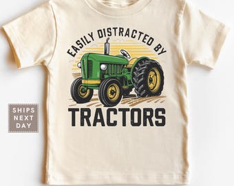 May include: Cream-colored toddler t-shirt featuring a green and yellow tractor graphic. The text above the tractor reads "EASILY DISTRACTED BY" and the text below reads "TRACTORS". The shirt is from Little Peekoos.