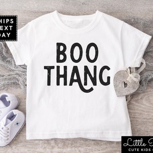 May include: White baby t-shirt with black text that reads "BOO THANG".