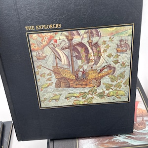 Puede incluir: Un libro negro titulado "THE EXPLORERS" con una colorida ilustraci&oacute;n de un velero en la portada. La imagen representa una escena hist&oacute;rica con m&uacute;ltiples barcos y criaturas marinas. El libro tiene un borde dorado.