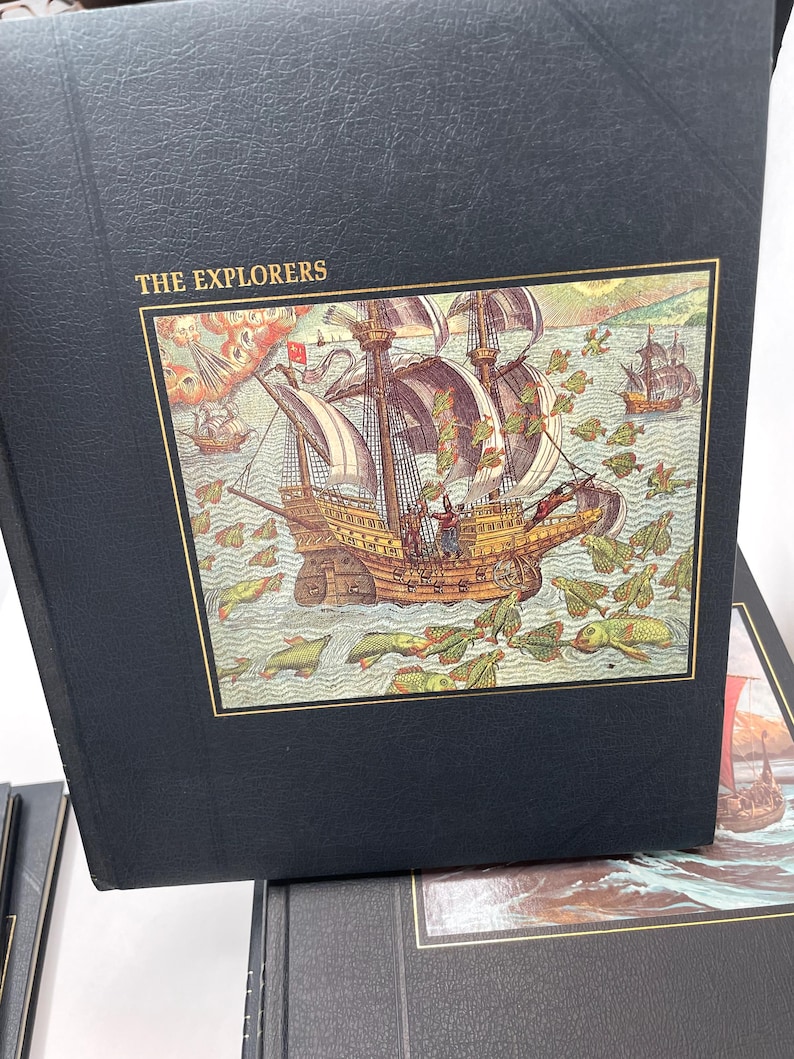 Puede incluir: Un libro negro titulado "THE EXPLORERS" con una colorida ilustraci&oacute;n de un velero en la portada. La imagen representa una escena hist&oacute;rica con m&uacute;ltiples barcos y criaturas marinas. El libro tiene un borde dorado.