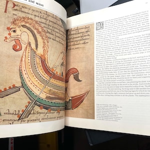 Puede incluir: P&aacute;gina de un libro abierto con una colorida ilustraci&oacute;n de un barco vikingo. El barco presenta una cabeza de drag&oacute;n, remos y un casco a rayas en rojo, amarillo, verde y azul. Texto en lat&iacute;n rodea la imagen.