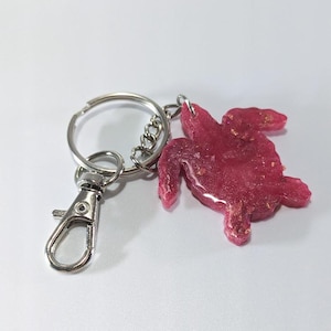May include: A pink glitter resin turtle keyring with a silver metal key ring and clasp.
