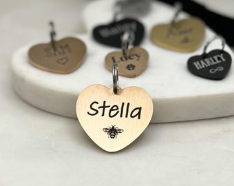 May include: A collection of gold heart-shaped pet ID tags with engraved names, including "Stella" with a bee design.
