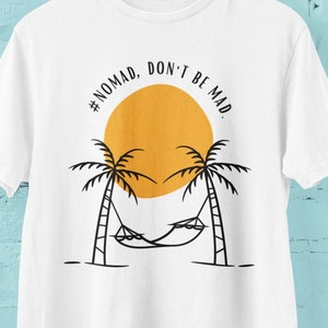 May include: White t-shirt with a black graphic design of palm trees, a hammock, and a yellow sun. The text '#NOMAD, DON'T BE MAD' is written in a black circle around the sun.