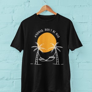 May include: Black t-shirt with a white graphic design of a hammock between two palm trees and a yellow sun with the text "#NOMAD. DON'T BE MAD."